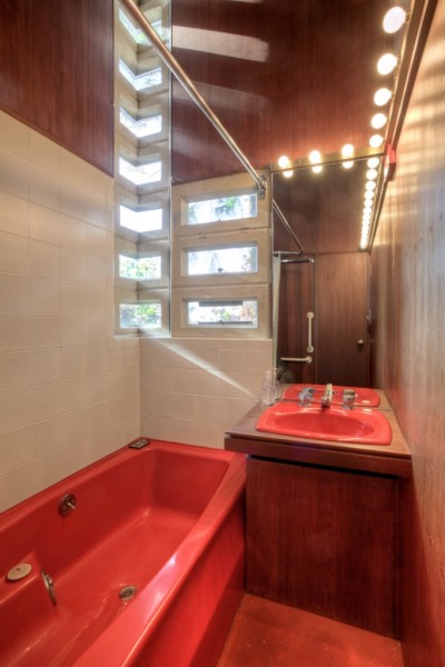 The mitered glass corner windows and the vanity's exposed light-bulbs in the bathroom. Image courtesy of Redfin. 